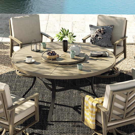 A round aluminum dining table with a slatted wood texture finish, accompanied by six chairs with cushions, displayed on a outdoor setting with a drink and a plant on the table.
