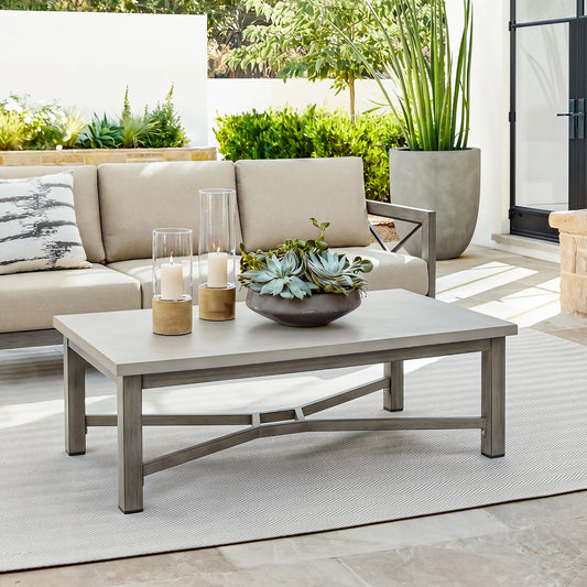 Outdoor patio set with beige sofa, coffee table, and decorative items on a patio.
