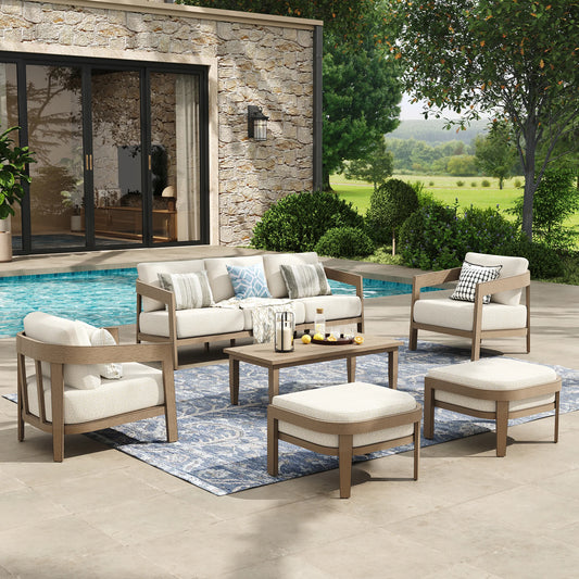 Outdoor patio furniture set with a sofa, chairs, and ottomans by a poolside.
