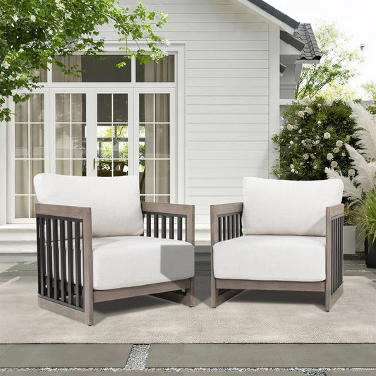 Two outdoor chairs with white cushions on a patio in front of a house.