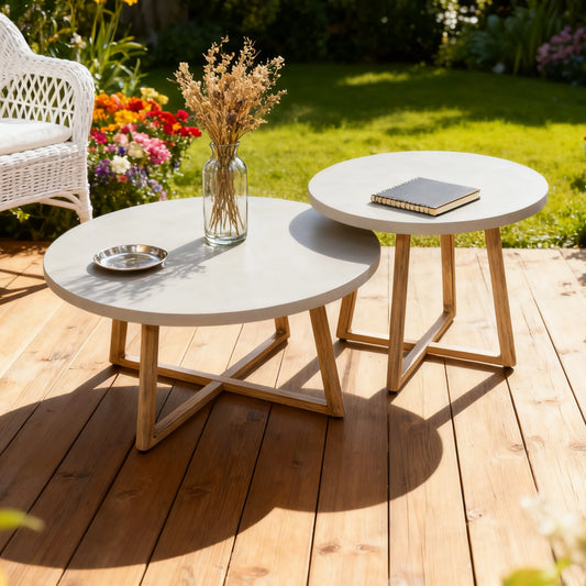 Two round outdoor tables with a vase of flowers and a book on a wooden deck.