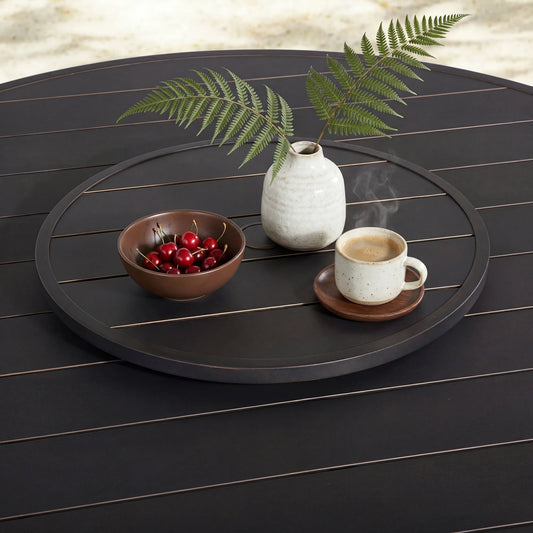 Round black tray with a cup, bowl, and vase on a wooden surface