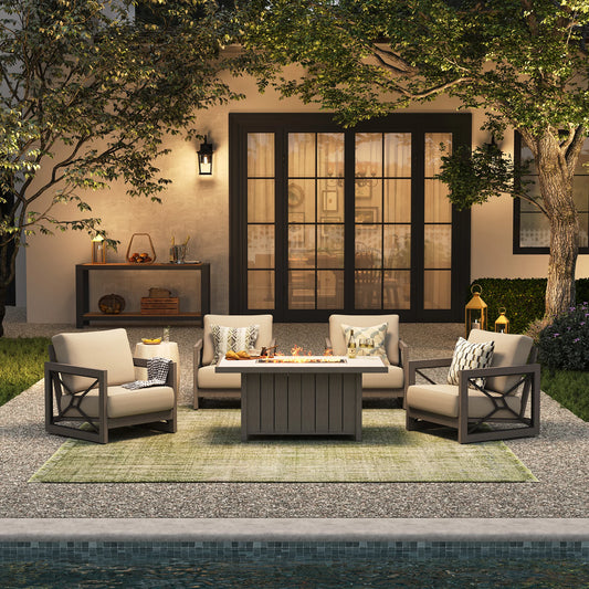 An elegant backyard entertaining space at twilight, showing the Marindo 5-piece gathering combo with glowing flames from the propane table throwing ambient light onto four stationary lounge chairs.
