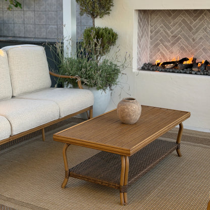 Outdoor patio with beige sofa, wooden coffee table, and fireplace.