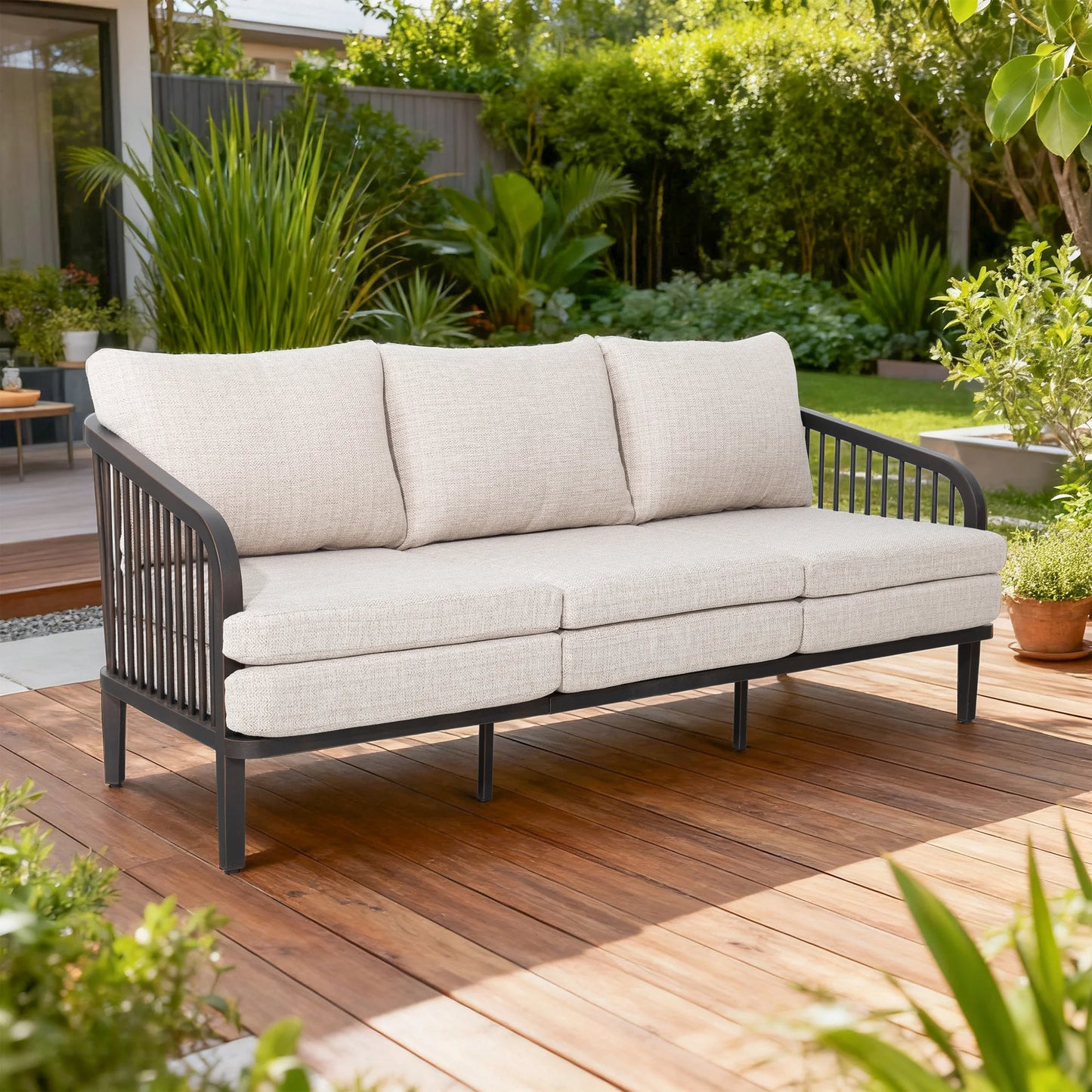 Outdoor sofa with beige cushions on a wooden deck surrounded by greenery