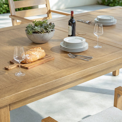 Close-up scene of the Alcudia aluminum outdoor dining table beautifully set with ceramic plates, wine glasses, bread, and a bottle of wine.