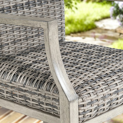 Close-up of a woven patio chair with a weathered gray steel frame and textured seat, overlaid with text reading 'Powder Coated Steel Frame' and feature badges 'Weathered Teak Look', 'Rust Proof', and 'Durable'.