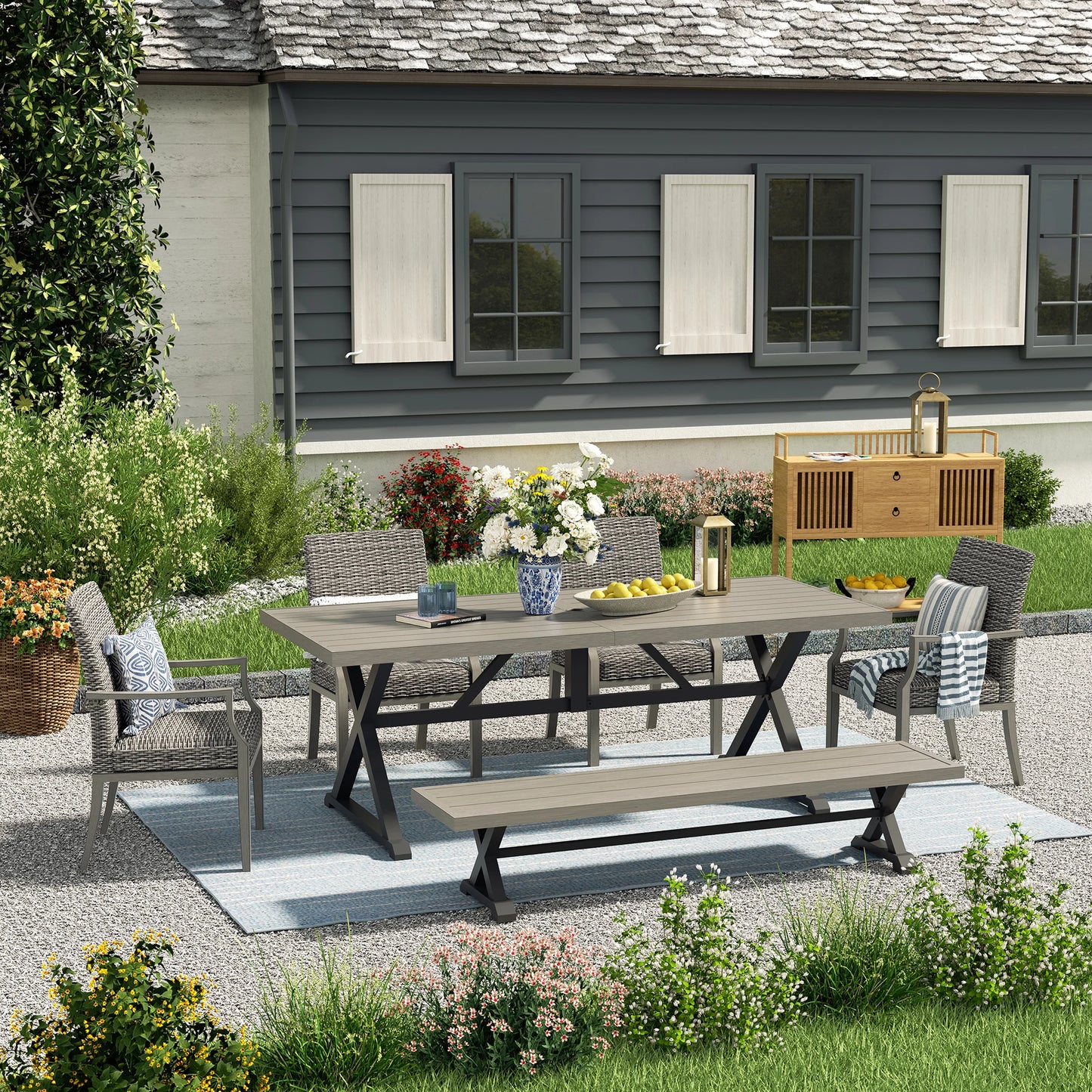 Outdoor patio set with table and chairs on a gravel patio in front of a house.