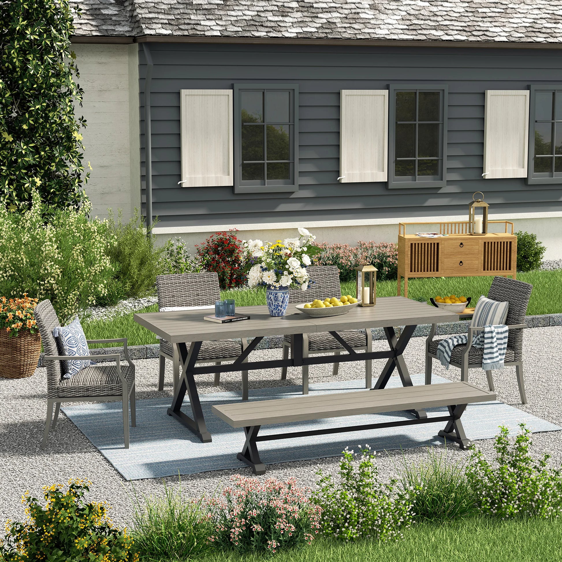 Outdoor patio set with table and chairs on a gravel patio in front of a house.