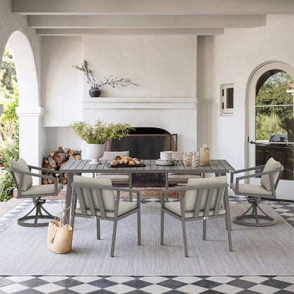 A dining set consisting of a rectangular gray wood-look table and four matching swivel chairs with light beige cushions, arranged on a light gray rug in a bright, modern patio dining room.