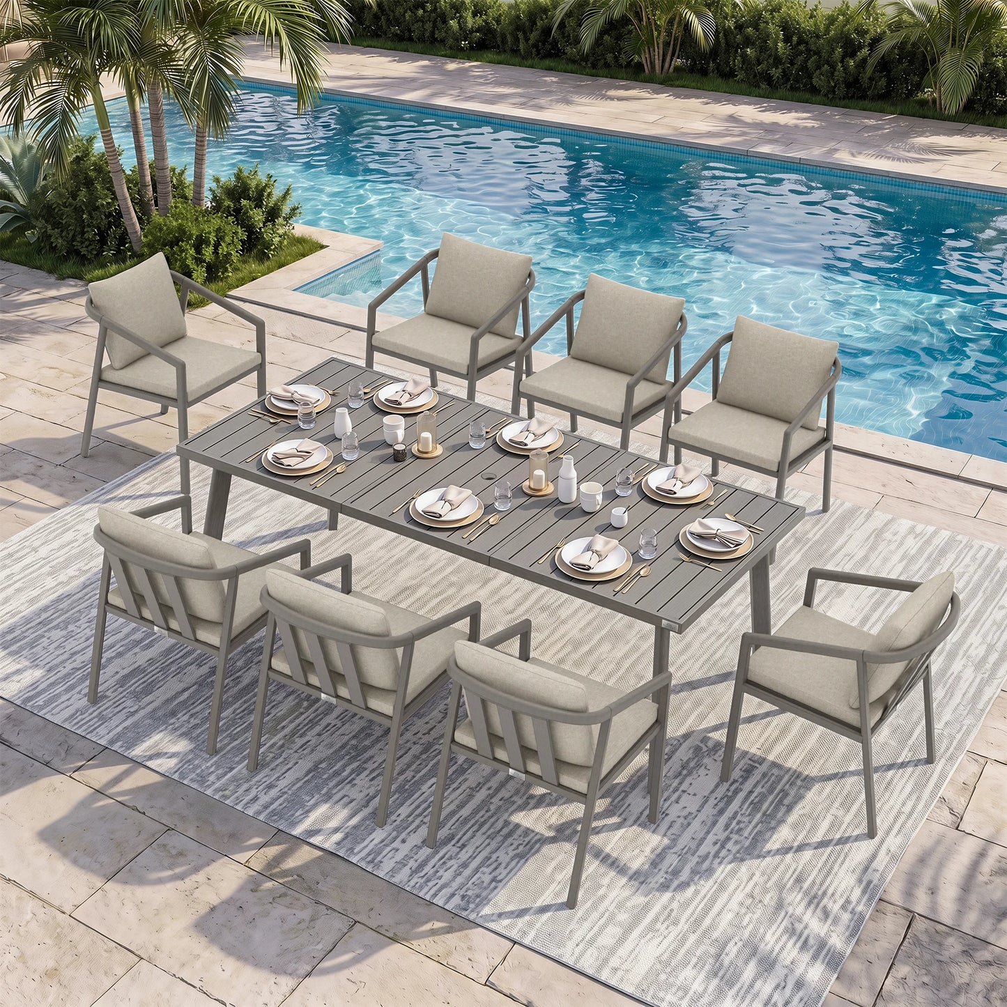 An 9-piece outdoor dining set with a rectangular gray slat-top table and eight matching armchairs with light beige cushions, arranged on a patterned rug beside a swimming pool.