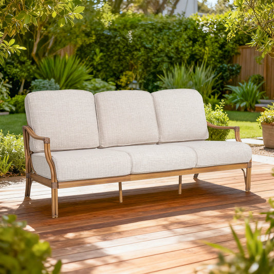 Beige outdoor sofa on a wooden deck with greenery in the background