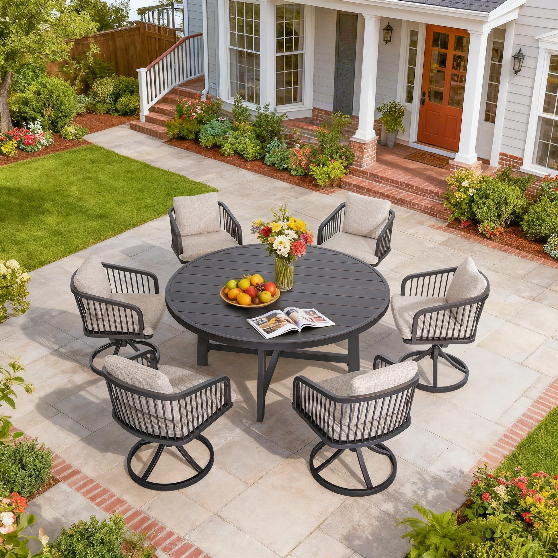 Outdoor patio set with a round table and chairs on a stone patio in front of a house.