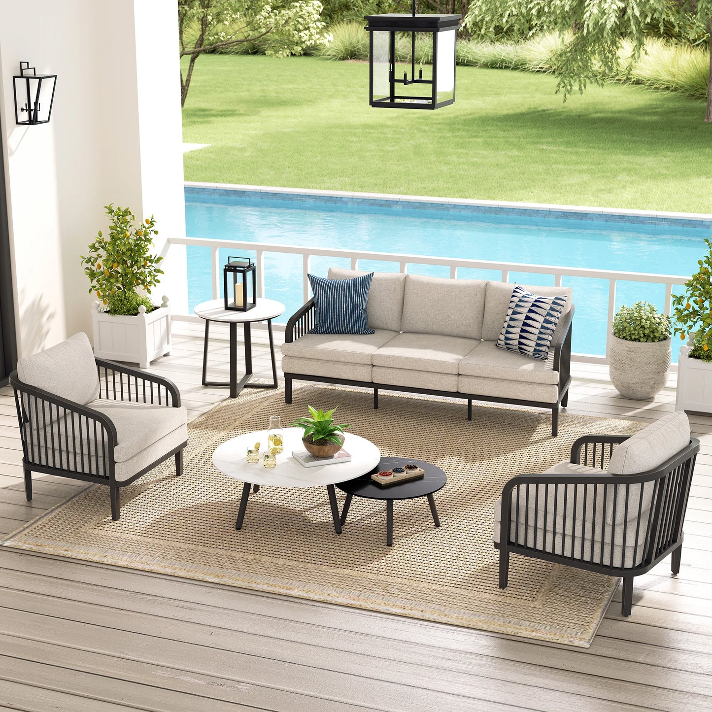 Outdoor patio set with sofa, chairs, and coffee table on a wooden deck by a pool.