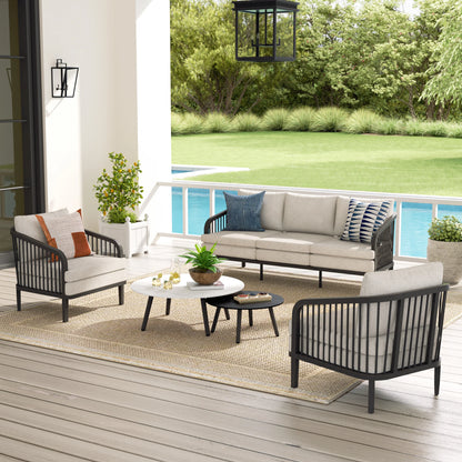 Outdoor patio furniture set with cushions on a deck overlooking a pool and garden.