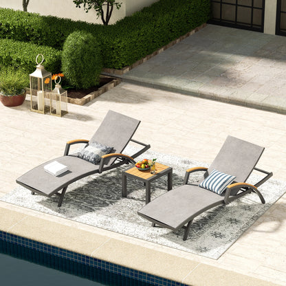Two lounge chairs with a small table by a poolside area.