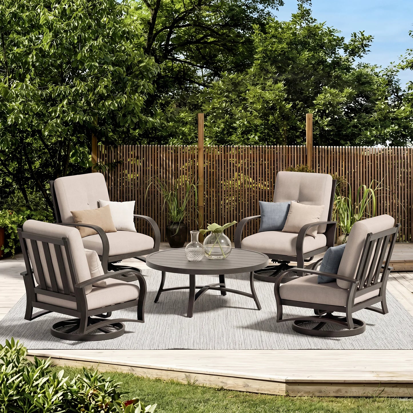 Outdoor patio set with four chairs and a table on a deck with greenery and a wooden fence in the background.