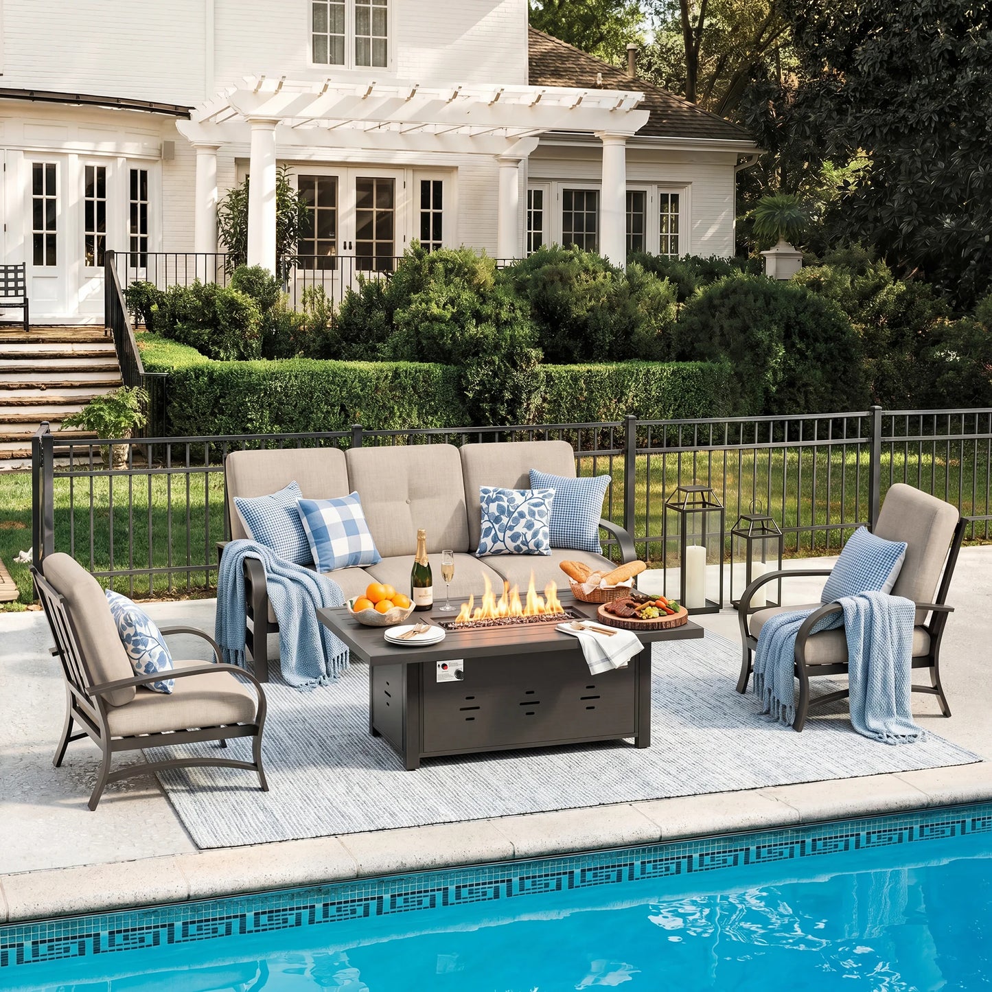Outdoor patio set with fire pit table by a poolside, featuring chairs, tables, and decorative items.