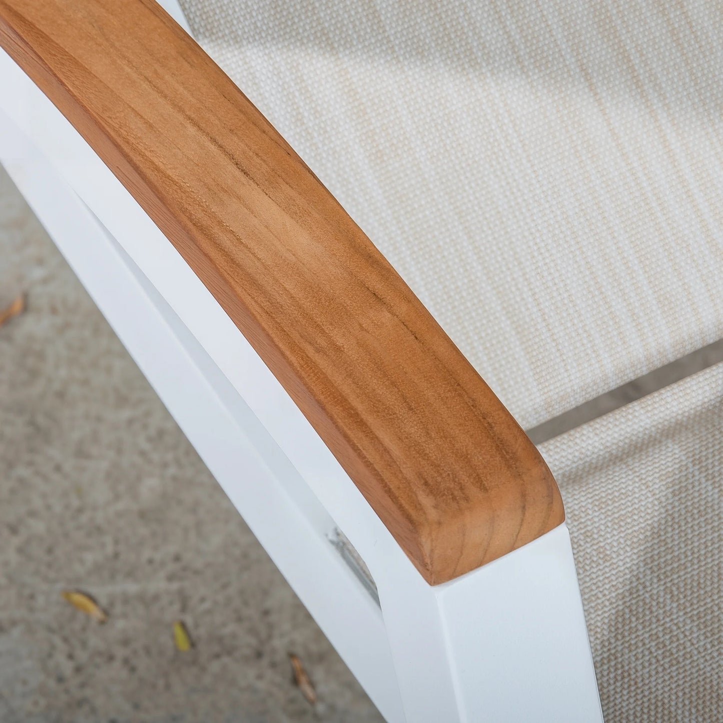 Close-up of a wooden chair armrest on a white chair with a textured beige background.