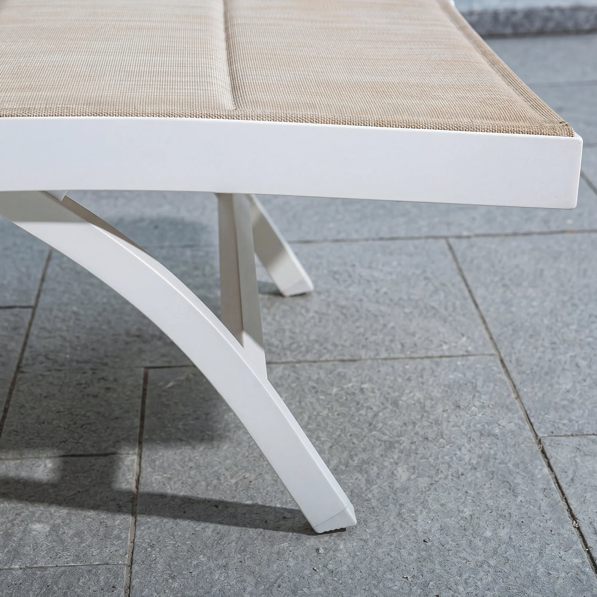 White outdoor chair with beige cushion on a tiled patio