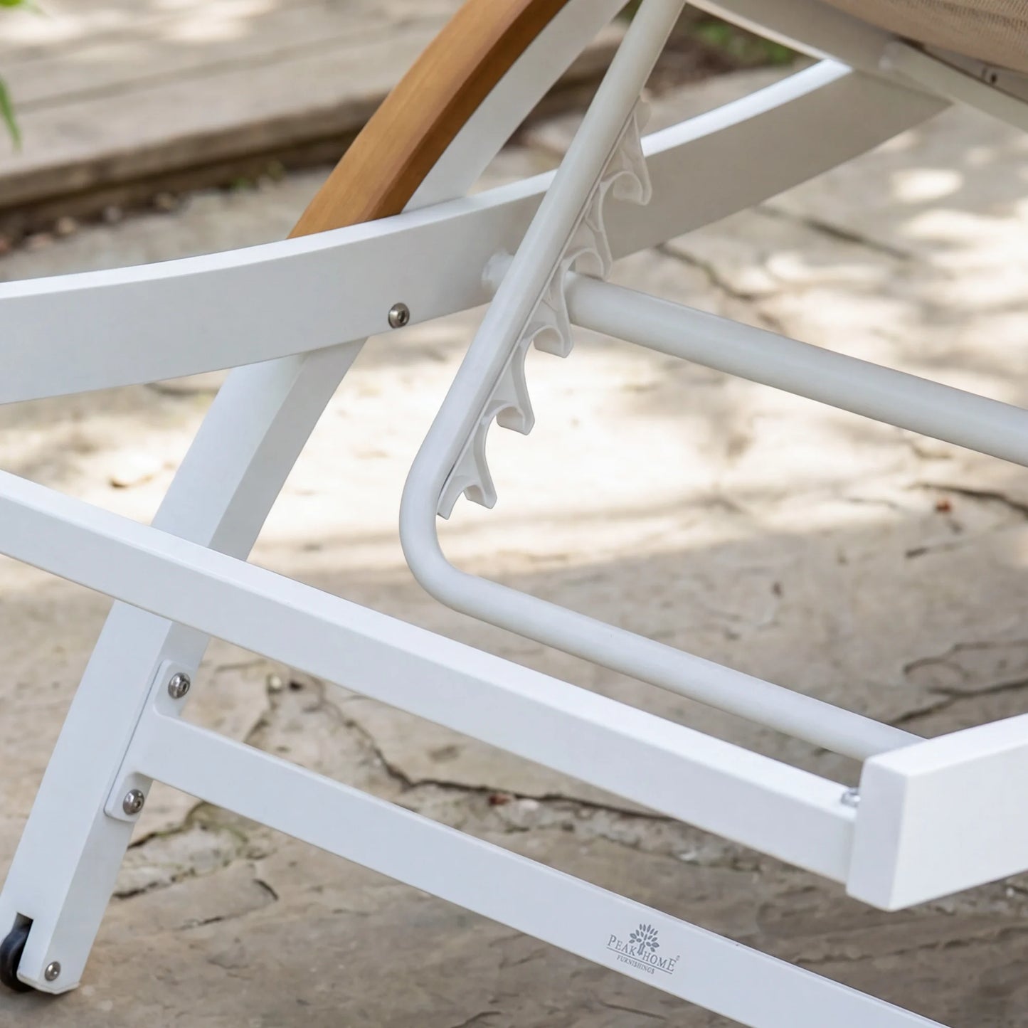 Close-up of a white metal chair with wooden armrest on a sandy surface.