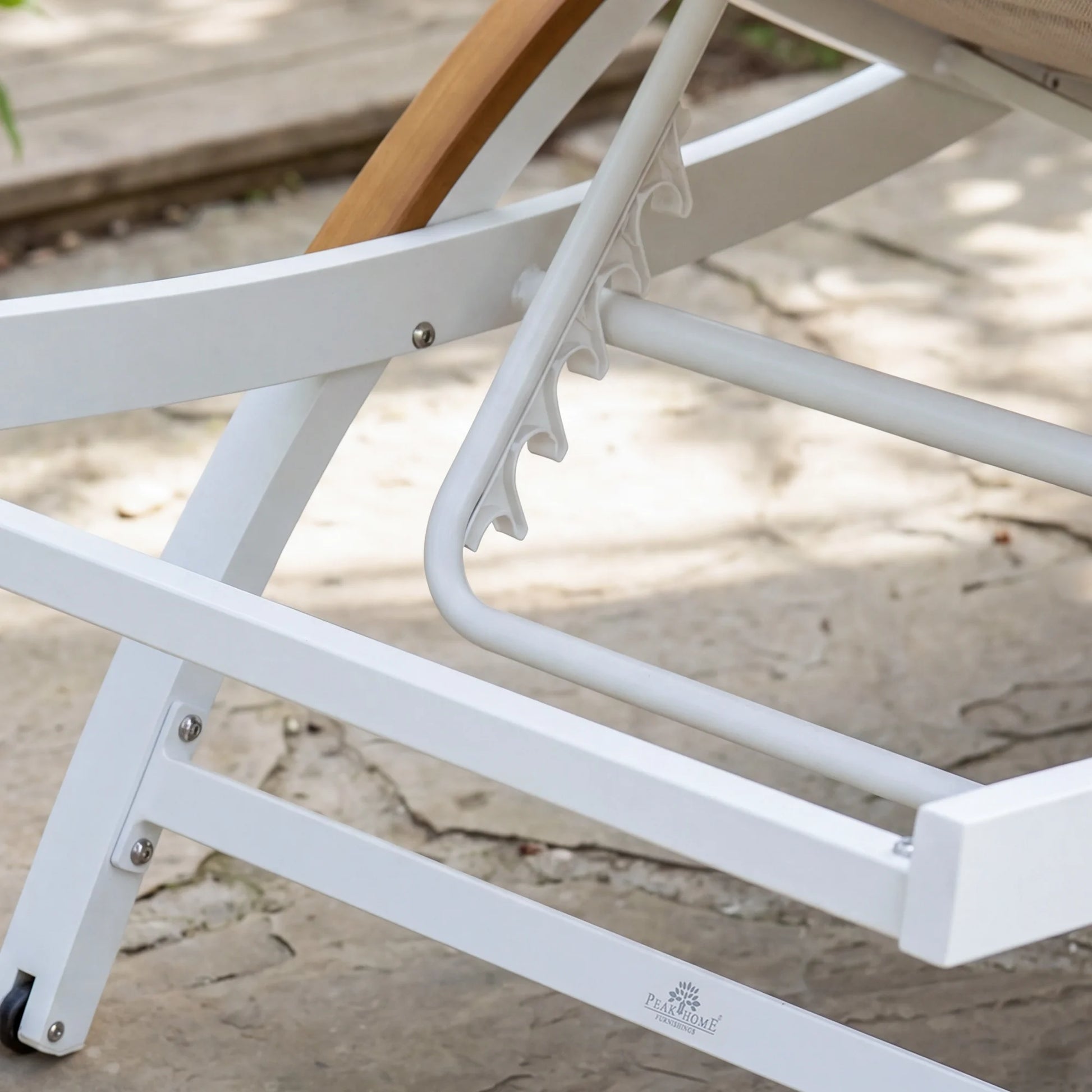 Close-up of a white metal chair with wooden armrest on a sandy surface.