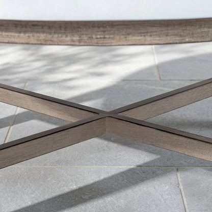 Close-up of a wood-look outdoor table with a cross-pattern on a tiled floor.