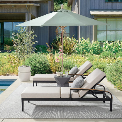 Outdoor patio set with lounge chairs, table, and umbrella on a patio with plants and pool in the background.