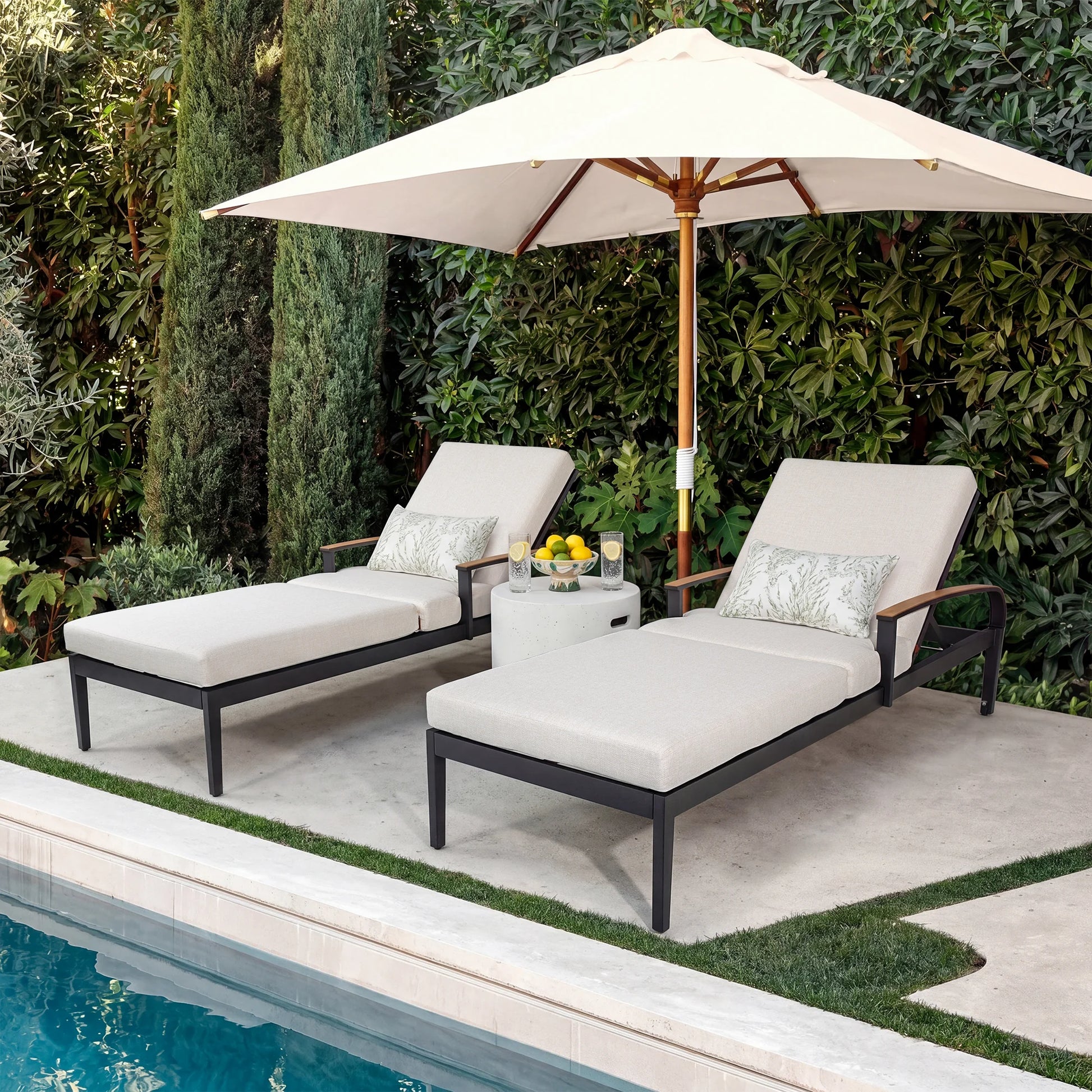 Two lounge chairs with a table and umbrella by a poolside