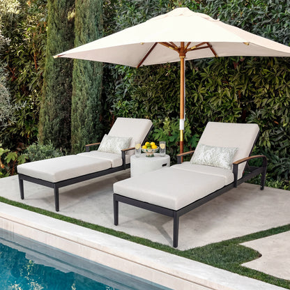 Two lounge chairs with a table and umbrella by a poolside