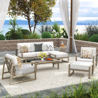 Outdoor patio set with white cushions and wooden frames on a patio with ocean view.