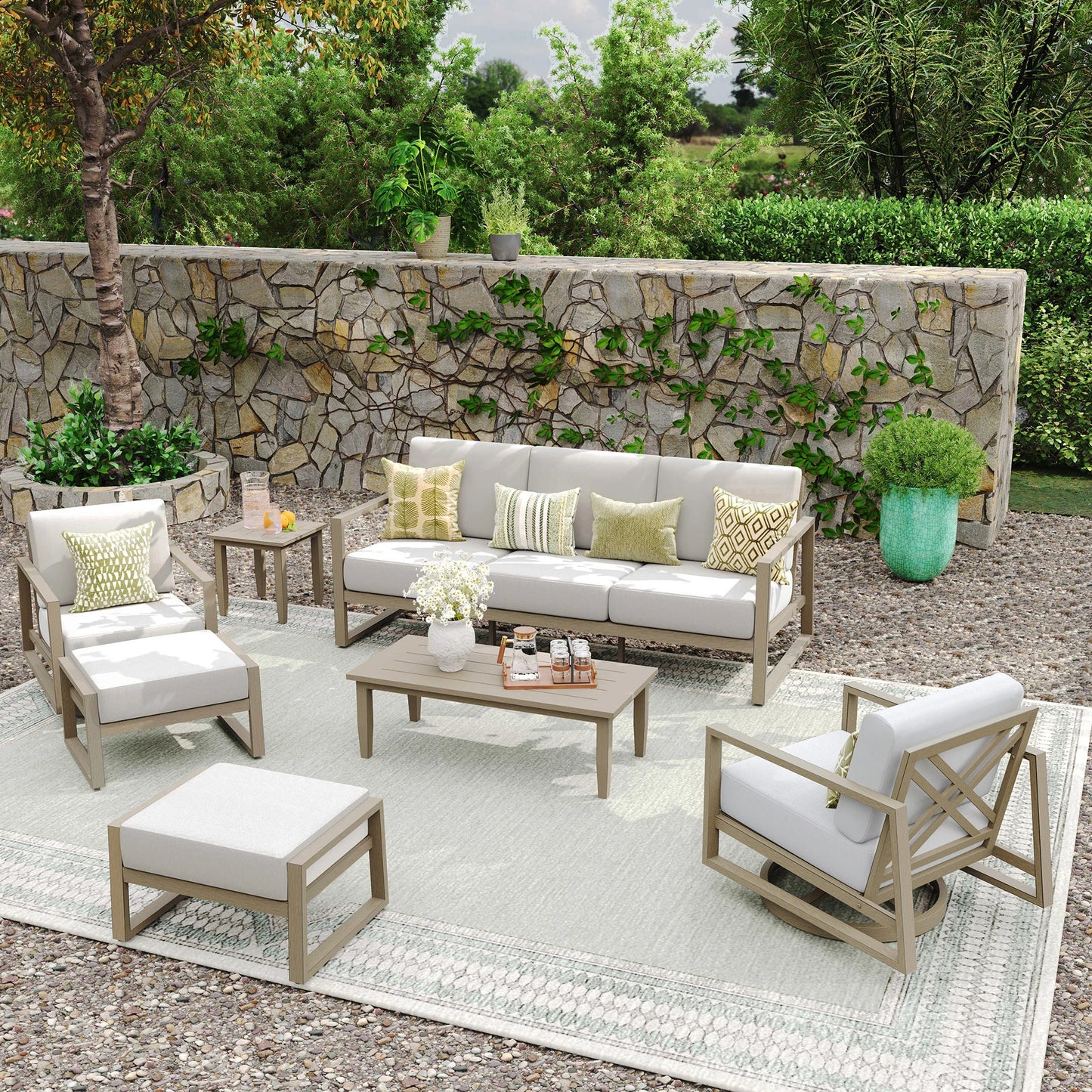 Outdoor patio set with furniture and decor against a stone wall.