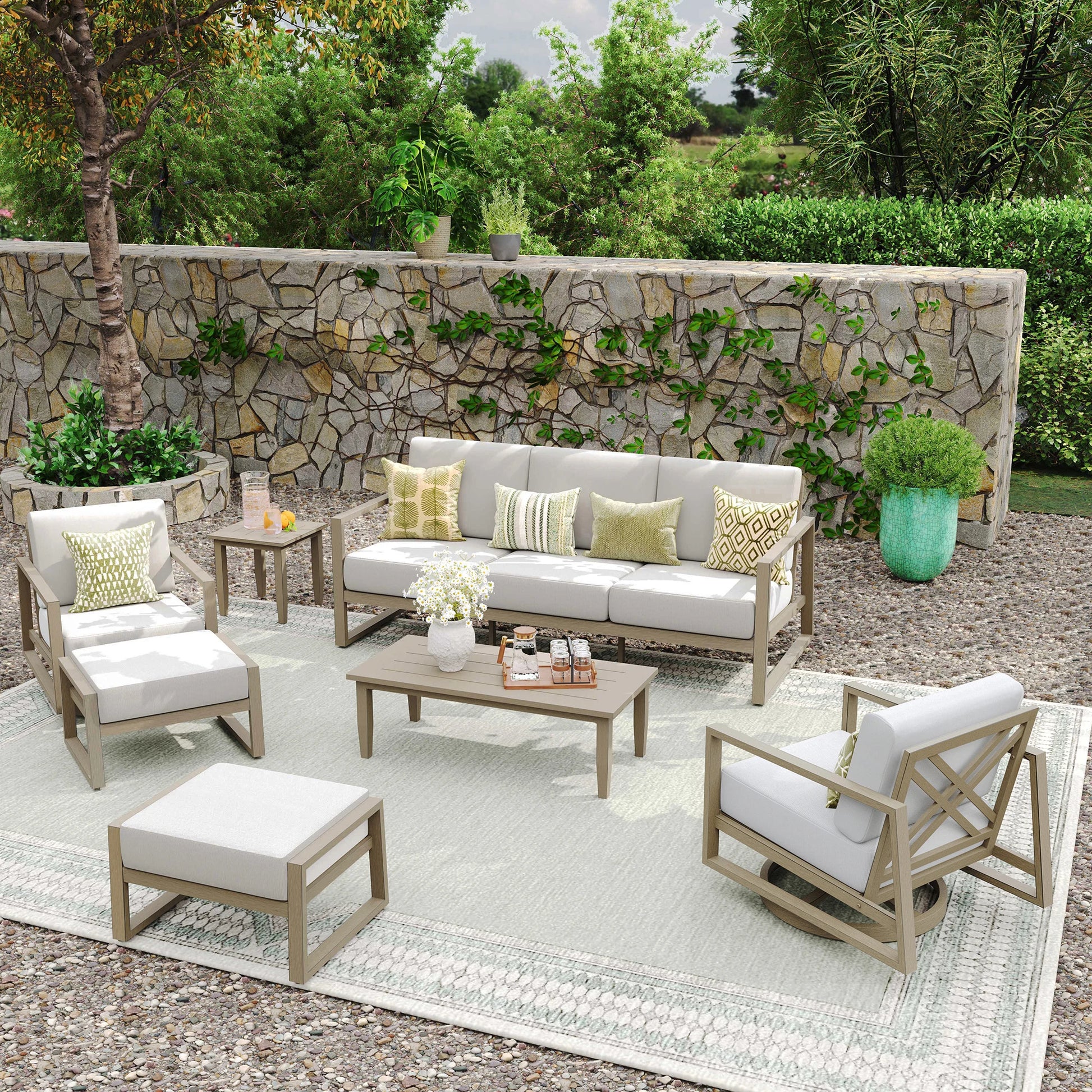 Outdoor patio set with furniture and decor against a stone wall.