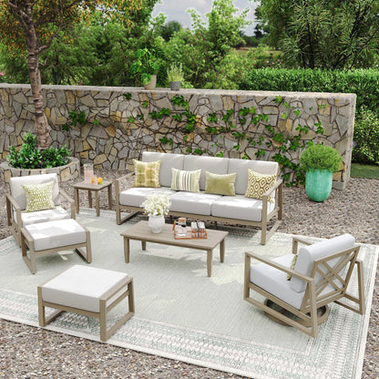 Outdoor patio set with furniture and decor against a stone wall.