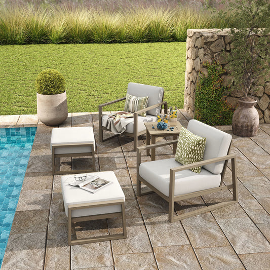 Outdoor patio set with chairs, table, and cushions by a pool