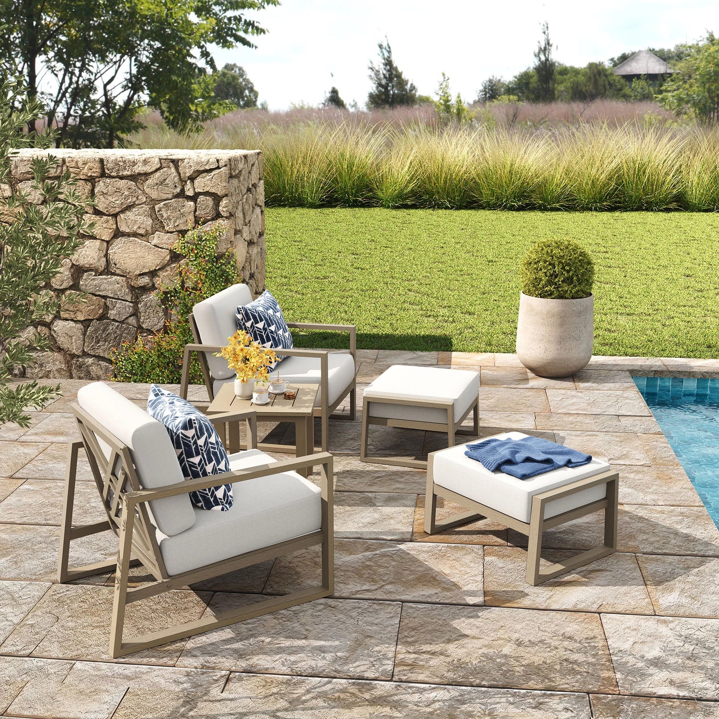 Outdoor patio furniture set with chairs, ottomans, and a table on a stone patio.