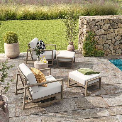 Outdoor patio set with chairs, table, and ottoman on a stone patio by a pool.