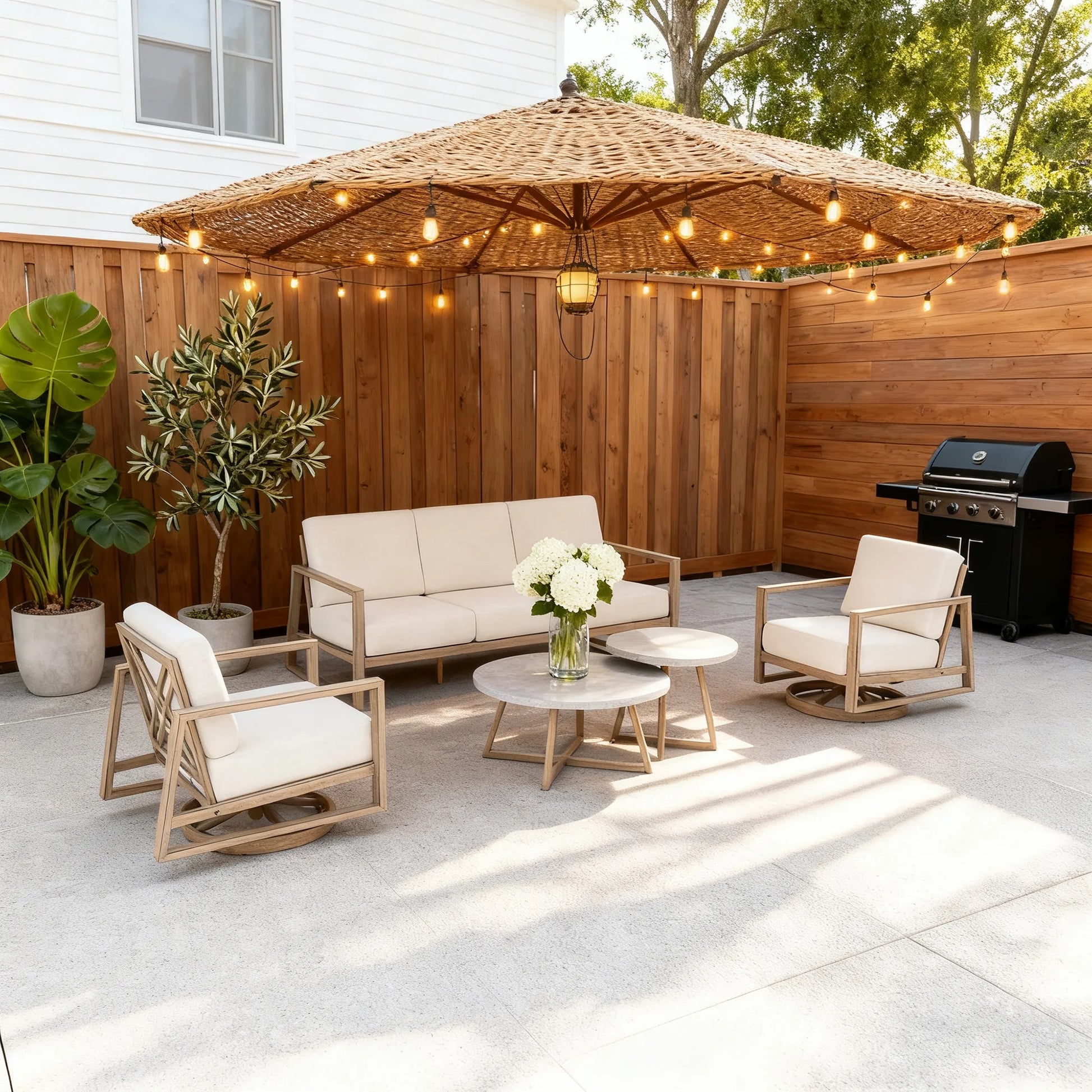 Outdoor patio set with furniture, umbrella, and string lights on a concrete patio.