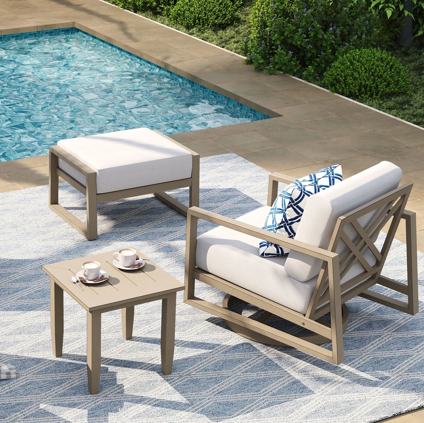 Outdoor patio set with chairs, table, and ottoman by a pool.