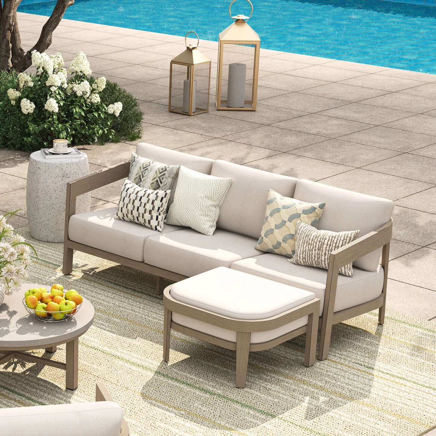 Outdoor patio set with a sofa, ottoman, and coffee table by a pool.