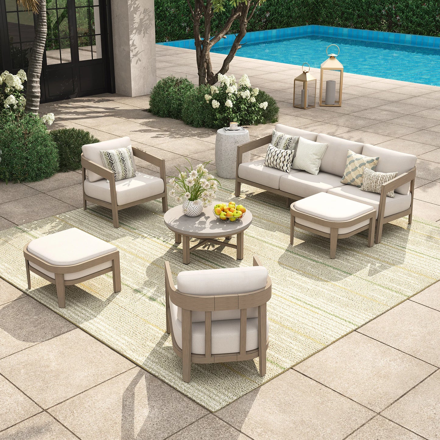 Outdoor patio furniture set with beige and white cushions by a pool.