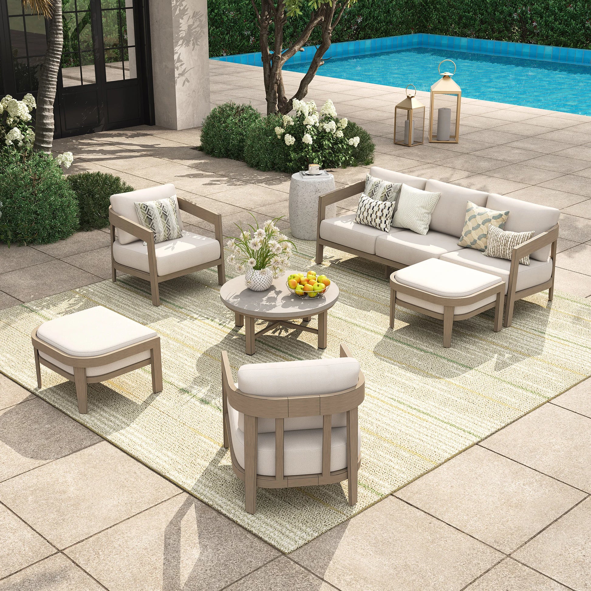 Outdoor patio furniture set with beige and white cushions by a pool.