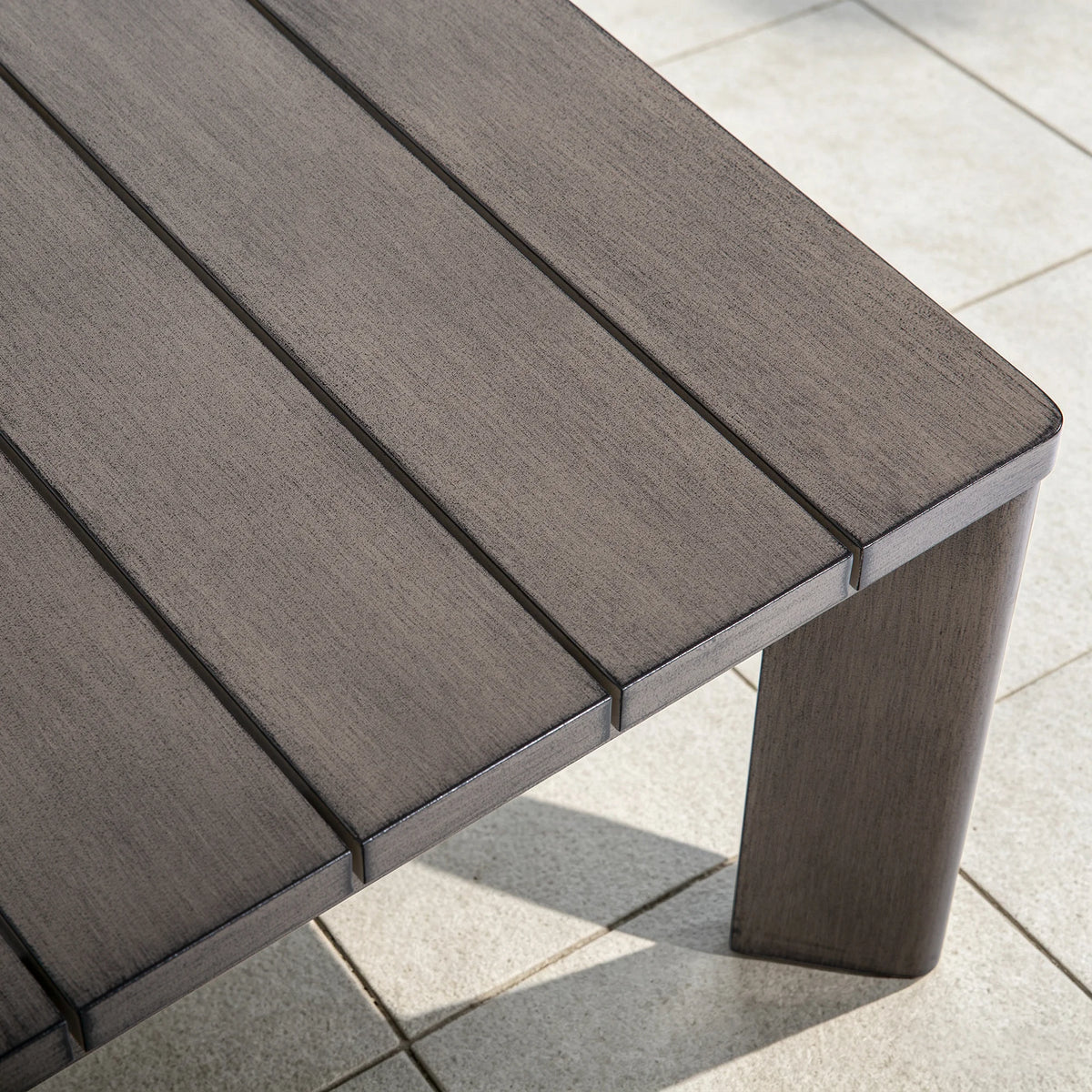Extreme close-up of the slatted tabletop showing the exquisite hand-brushed wood-grain painted finish on the durable aluminum frame.