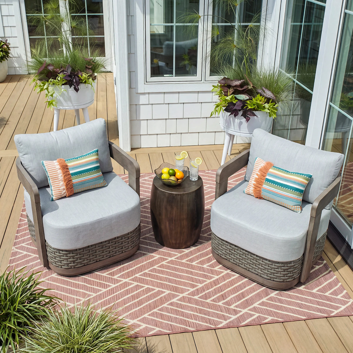 High-angle view of two Manarola fixed outdoor chairs styled with throw pillows on a beautiful home deck patio setup.