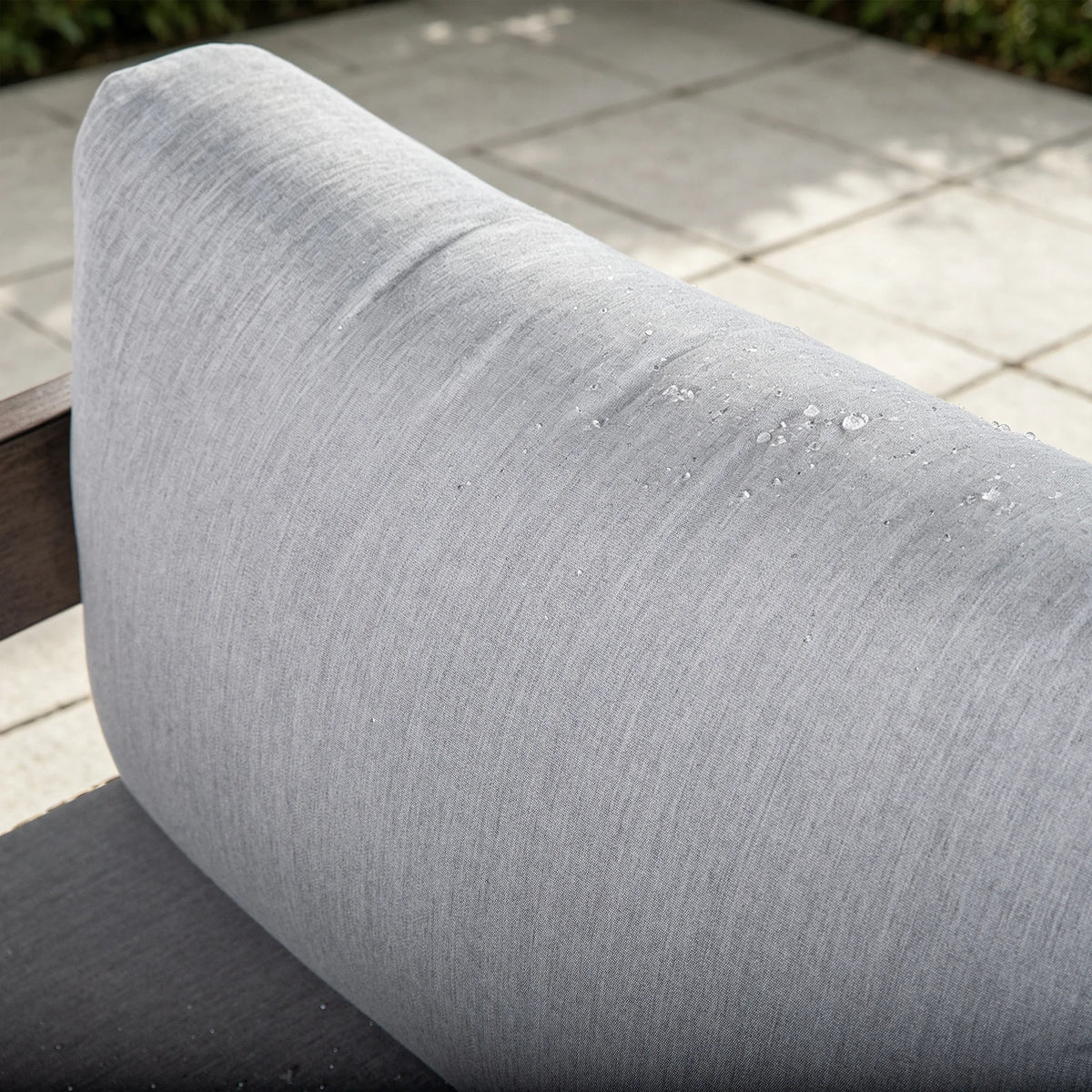 Close-up of water droplets effortlessly sliding off the premium gray Sunbrella back cushion of the outdoor chair.

