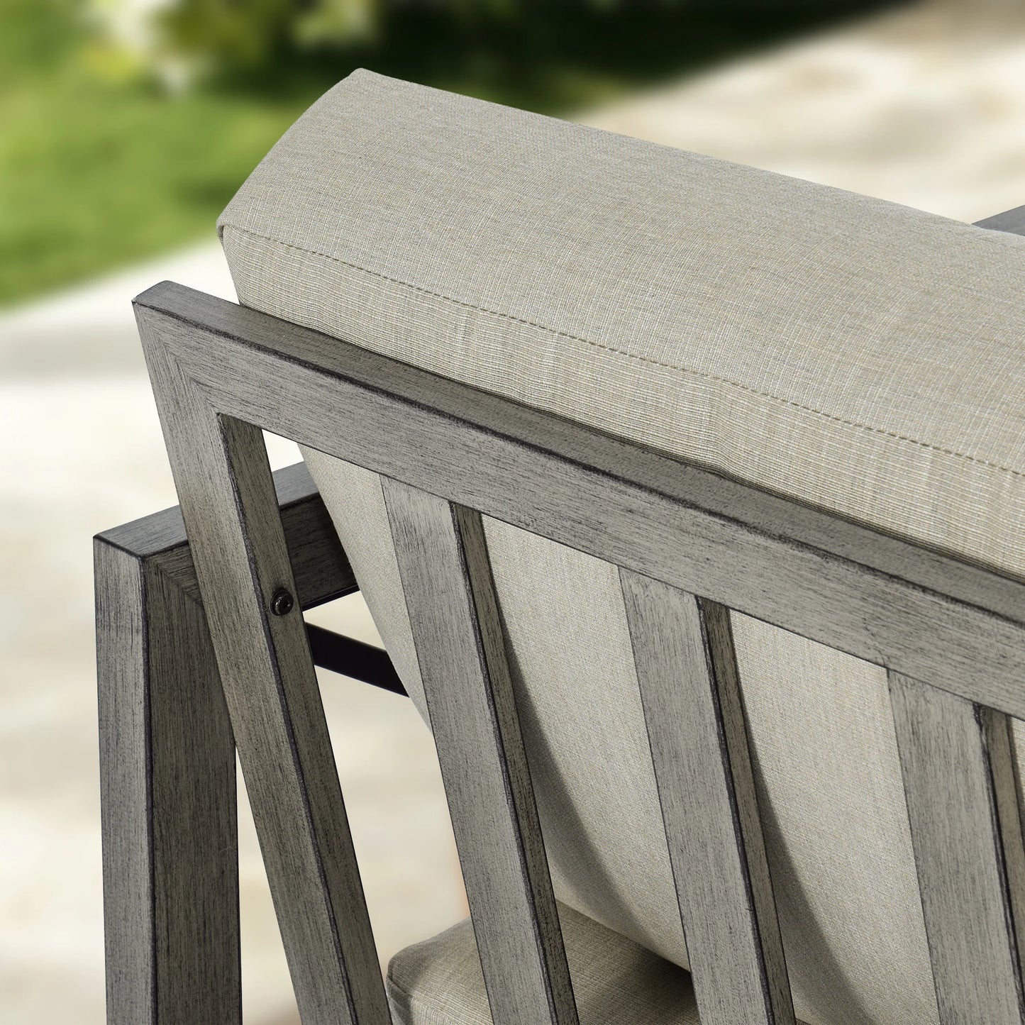 Close-up of a wood-look chair with a gray cushion on a blurred outdoor background
