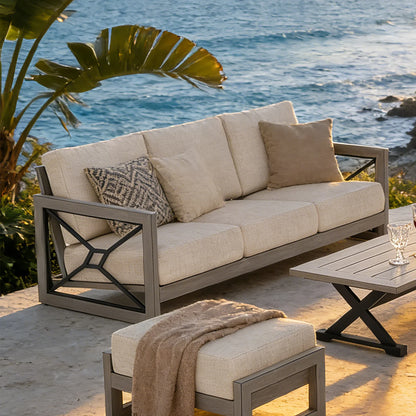 Outdoor patio set with beige cushions and a small table by the ocean.