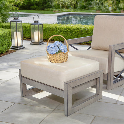 Outdoor patio set with ottoman, chair, and lanterns near a pool.
