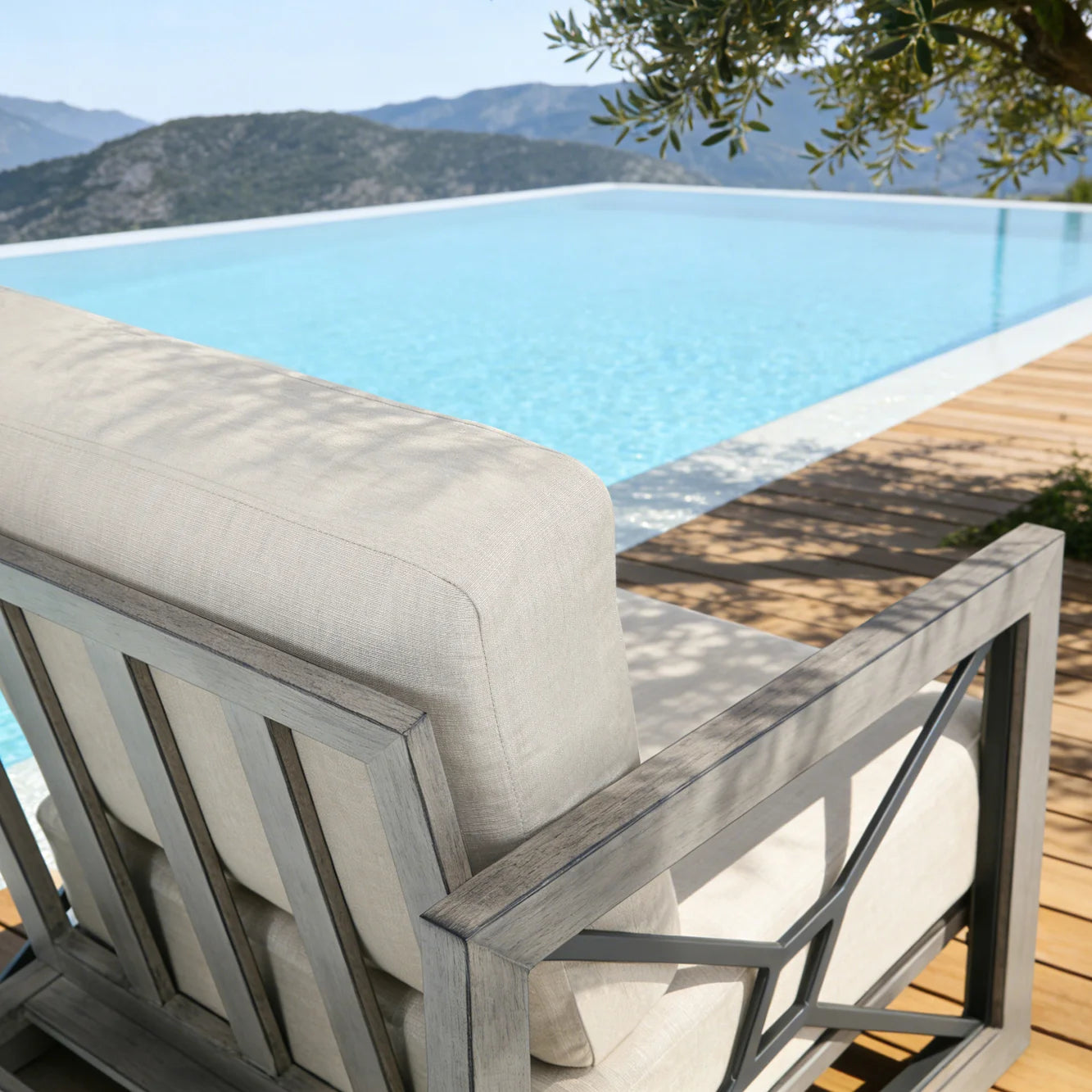 Chair with cushion by an infinity pool with a mountainous landscape in the background