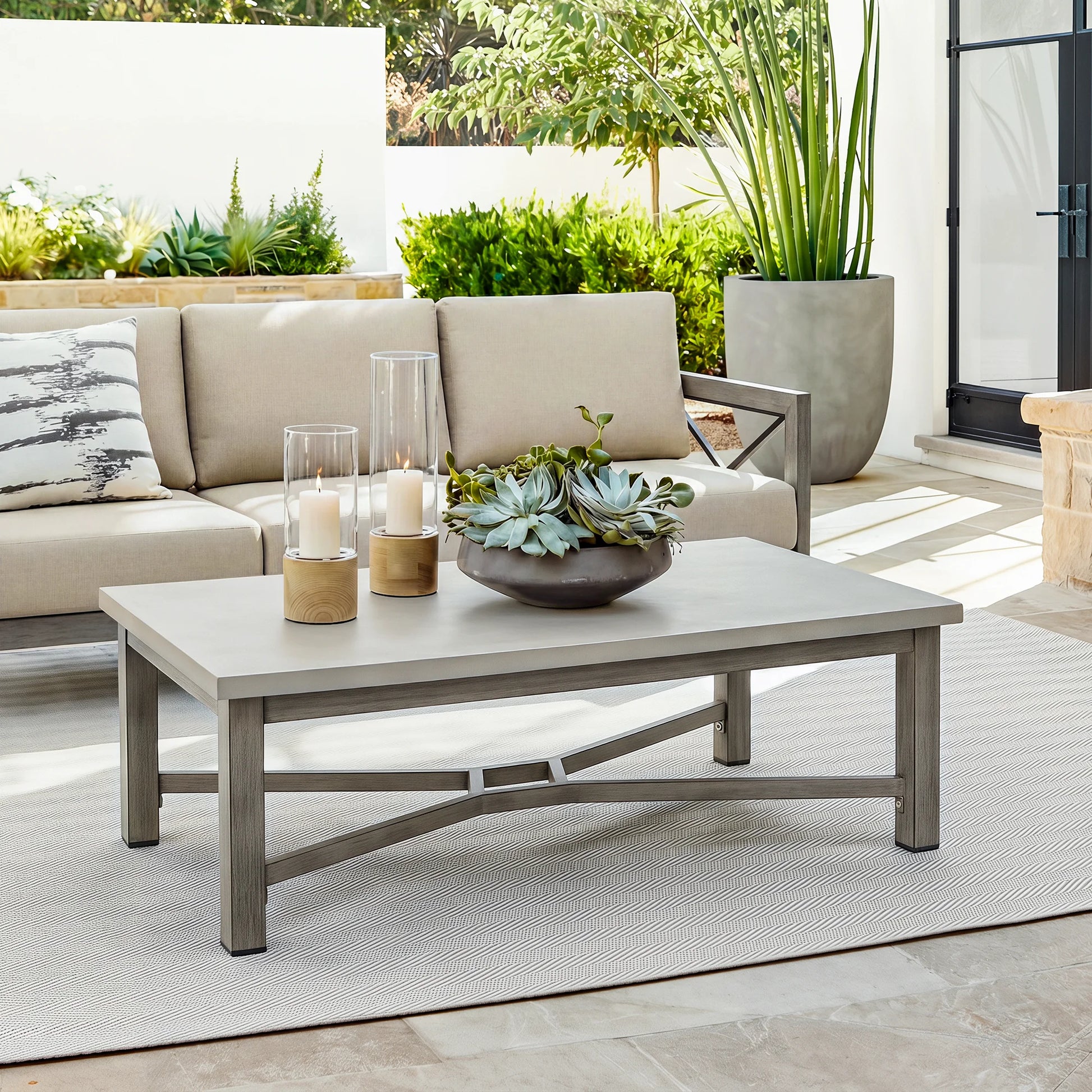 Outdoor patio set with beige sofa, coffee table, and decorative items on a patio.